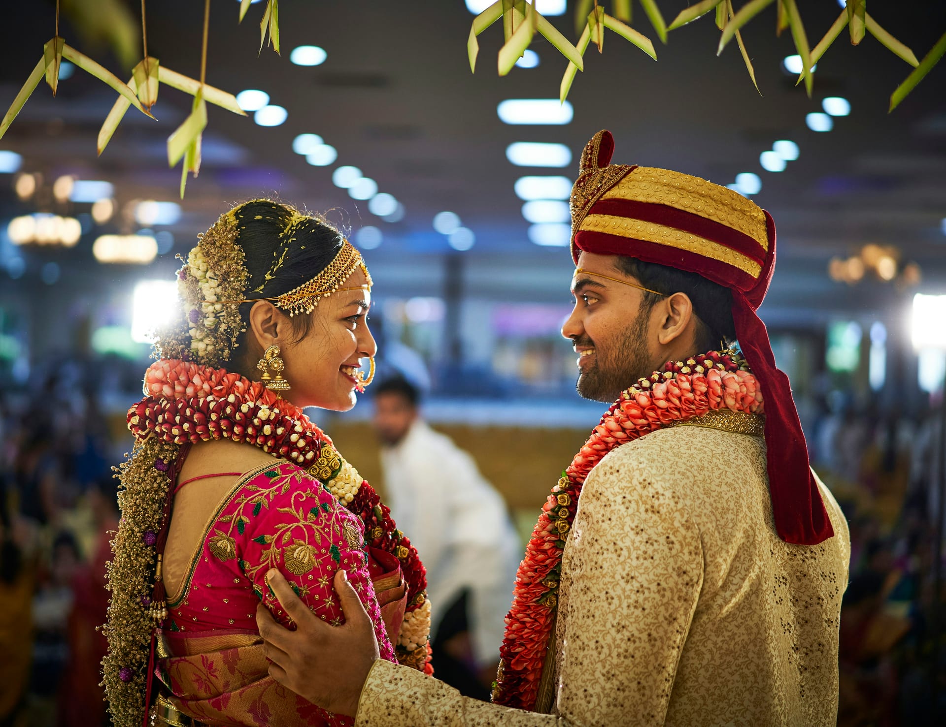Happy couple in traditional Indian wedding attire exchanging garlands during ceremony