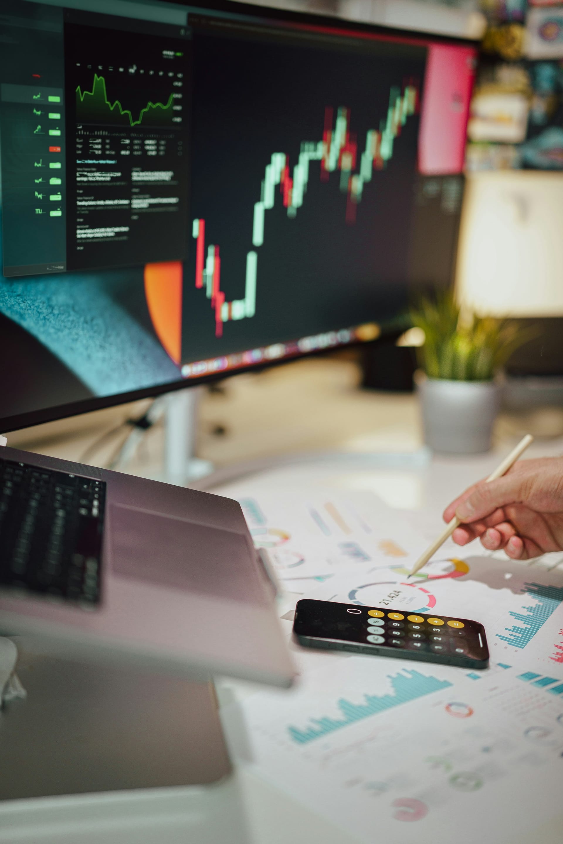 Financial charts and graphs displayed on laptop screen with calculator and documents